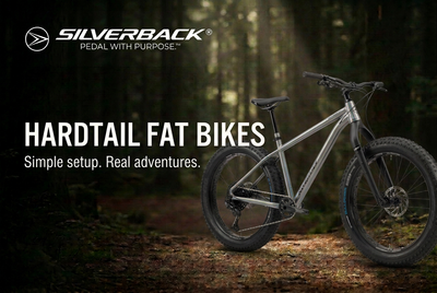 Silver-grey Silverback SE:Series Fat Explorer with rigid carbon fork and wide fat tyres on a forest trail beneath a Hardtail Fat Bikes title and white Silverback logo