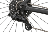 Close-up of a bicycle rear derailleur and cassette with chainring and chain, shown on a white background. 2