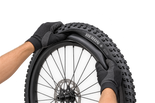 Illustrative gloved hands fitting an inner tube into a Maxxis Rekon+ tyre 4