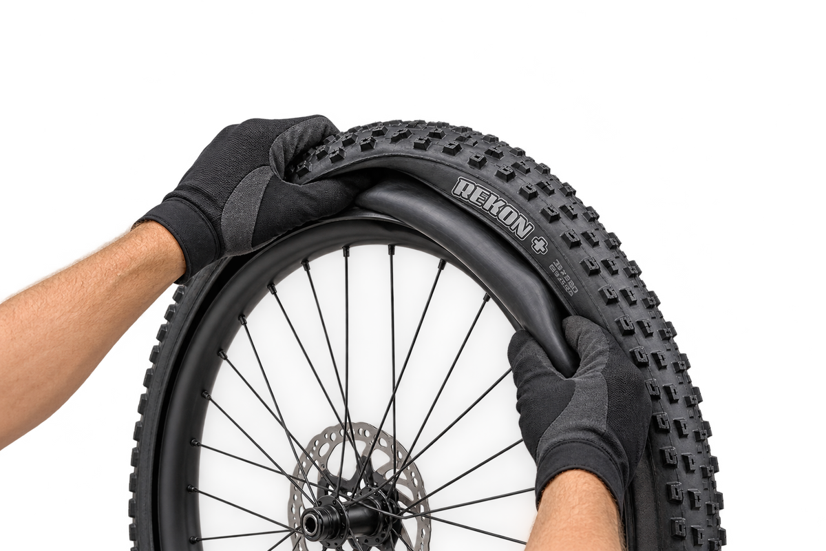 Illustrative gloved hands fitting an inner tube into a Maxxis Rekon+ tyre 4