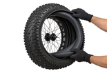 Illustration of gloved hands fitting a fatbike inner tube into a Vee Bulldozer tyre 2