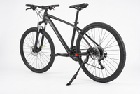 A black mountain bike with a black frame, black tires, and a black kickstand, photographed on a seamless white studio background. 4