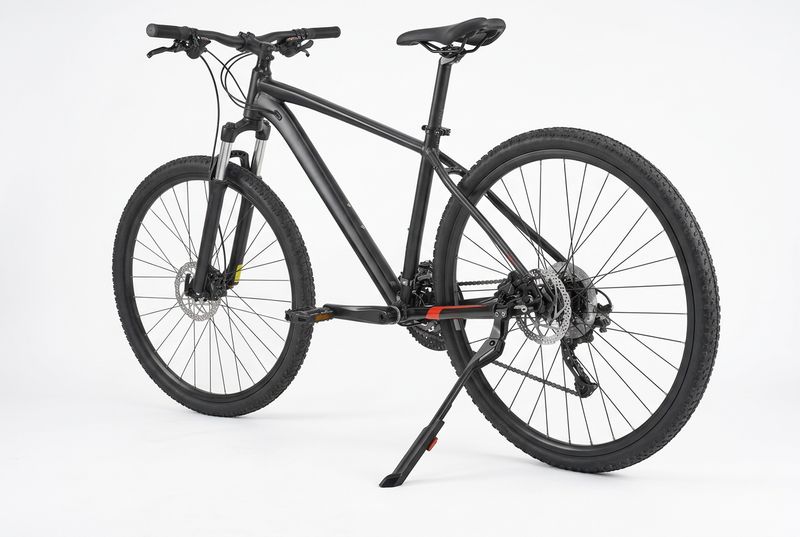 A black mountain bike with a black frame, black tires, and a black kickstand, photographed on a seamless white studio background.