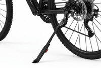 Close-up of a bicycle's rear wheel and black kickstand on a clean white background, showing the stand supporting the frame near the wheel hub. 1