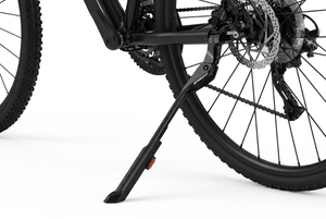 Close-up of a bicycle's rear wheel and black kickstand on a clean white background, showing the stand supporting the frame near the wheel hub.